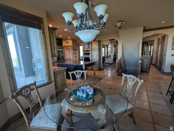 Stone tile flooring extending throughout, custom wood cabinetry, an arched entryway, and a built-in kitchen island with a stone countertop