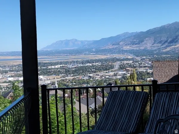 Expansive balcony with black wrought iron railing, overlooking a vast urban landscape and distant mountains