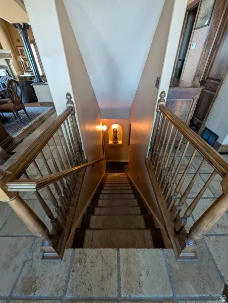 Staircase with wood balusters and handrails, stone tile flooring, and integrated wall niche lighting