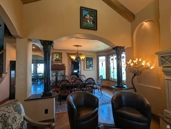 Arched entryway with decorative columns, transom windows, wood-finish flooring, and a chandelier