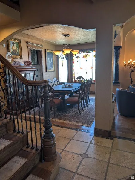 Tiled flooring with contrasting border, ornate wrought iron railing, custom carved wood newel post, arched entryway, and a built-in cabinet