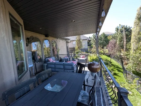 Covered balcony featuring a dining area, arched windows, recessed lighting, and decorative railing