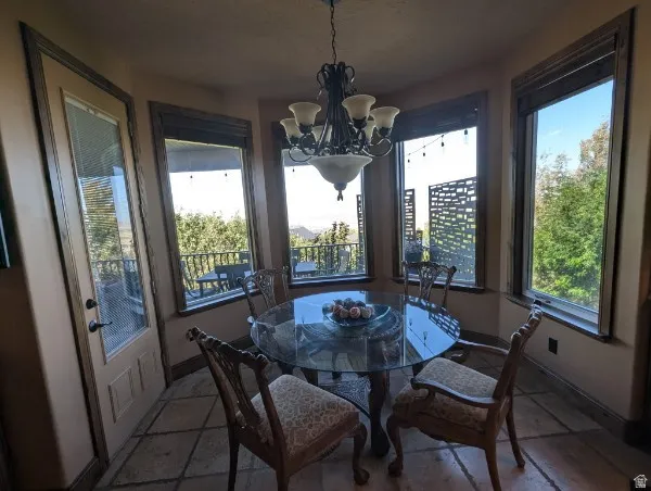 Bay window dining area with tile flooring, an exterior door, and a multi-arm chandelier