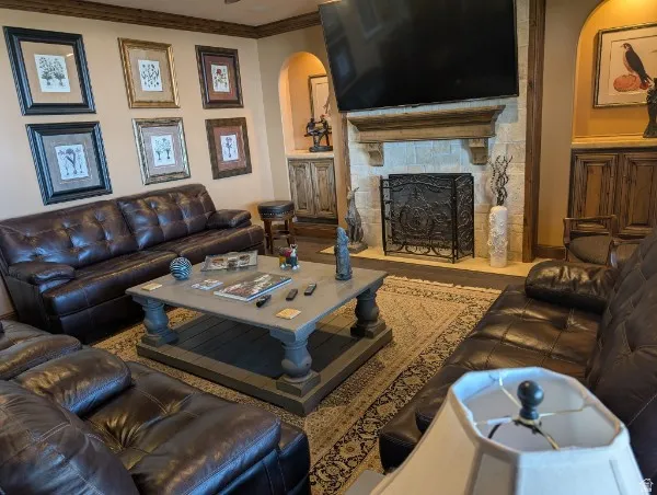 Stone fireplace with an ornate iron screen, wood-beamed ceiling, and built-in cabinetry