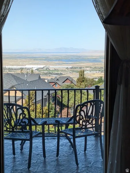 Primary bedroom balcony access through glass doors, metal balcony railing, and expansive distant scenery