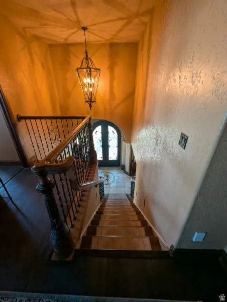 Grand entryway featuring a decorative chandelier, wrought iron staircase railing, and a wood-finish handrail