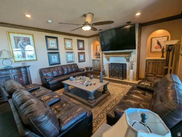 Stone fireplace with an ornate iron screen, recessed lighting, ceiling fan, and built-in cabinetry with arched alcoves