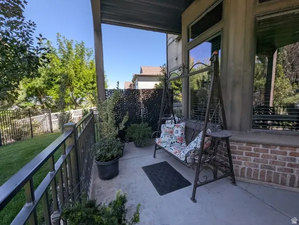 Covered patio featuring concrete flooring and a wrought iron railing