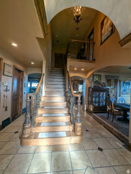 Grand staircase with wrought iron balusters and wood-finish treads, complemented by a tile flooring with accent squares