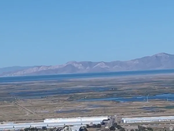 Expansive natural landscape featuring a prominent body of water, distant mountains, and varied terrain