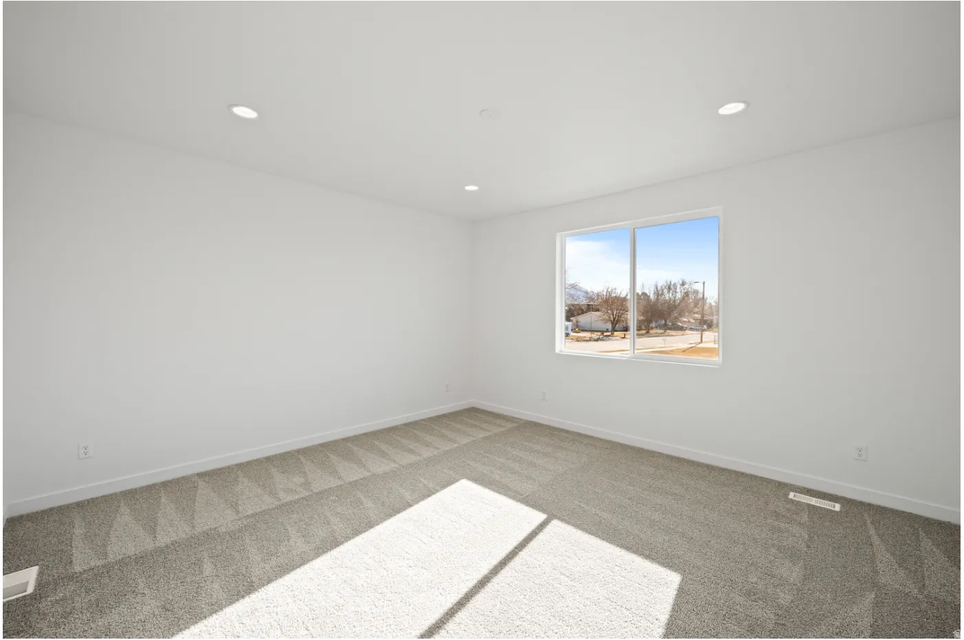 Recessed ceiling lighting, white painted walls, and a large window