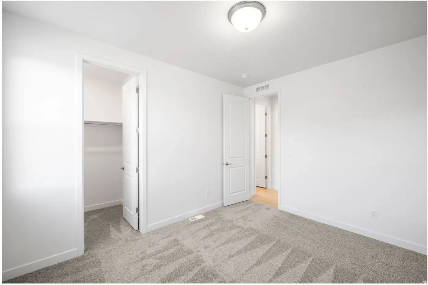Neutral-toned carpeting, white painted walls, and a flush mount ceiling light fixture