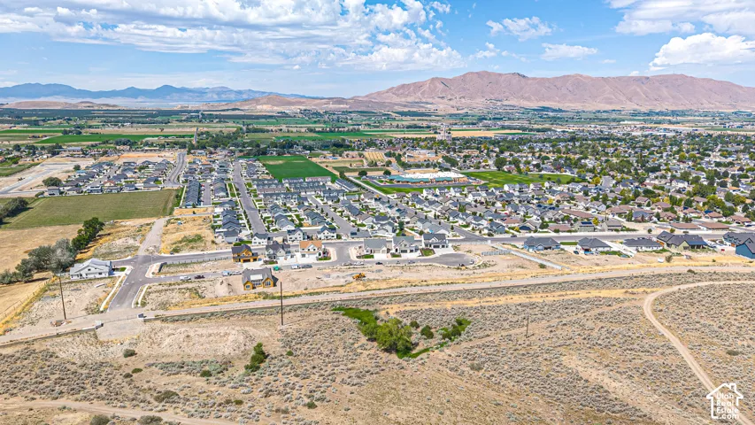 Expansive residential development with numerous single-family homes, surrounded by agricultural fields and distant mountains