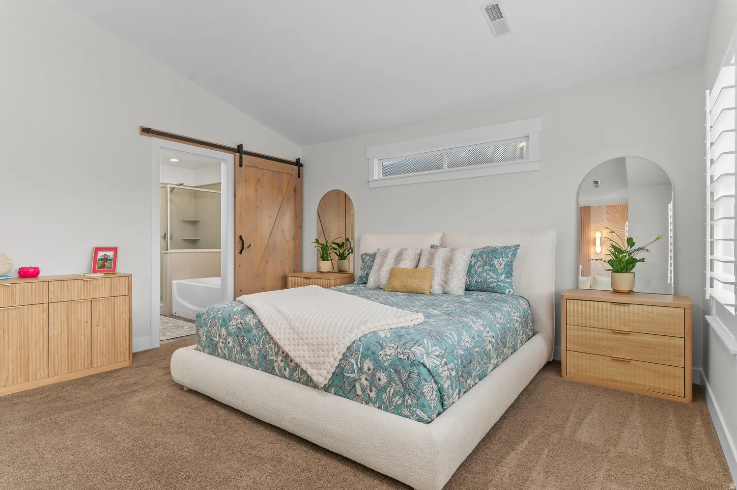 Vaulted ceiling, transom window, plantation shutters, barn door entry, and carpet flooring