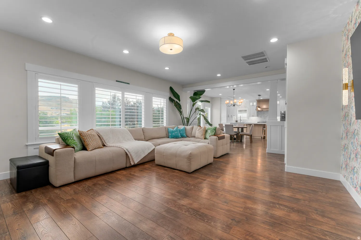 Wood-finish flooring, recessed lighting, and a drum ceiling fixture illuminate this open-concept space