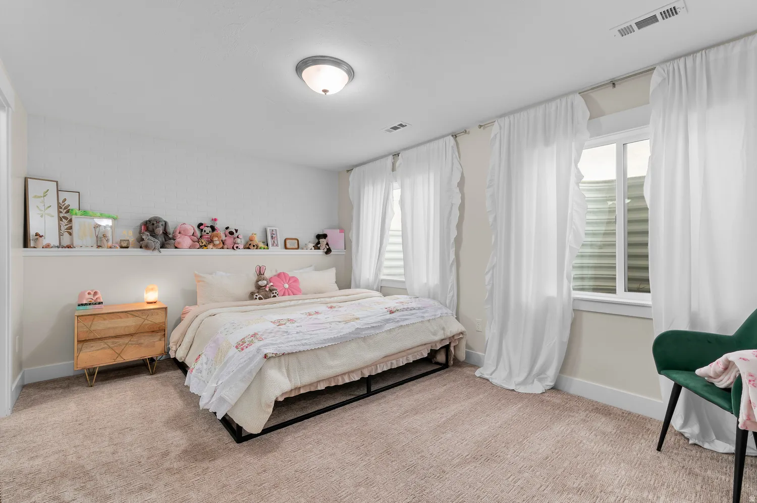 Recessed wall shelving, overhead flush mount lighting, two windows with blinds, and neutral tone carpeting