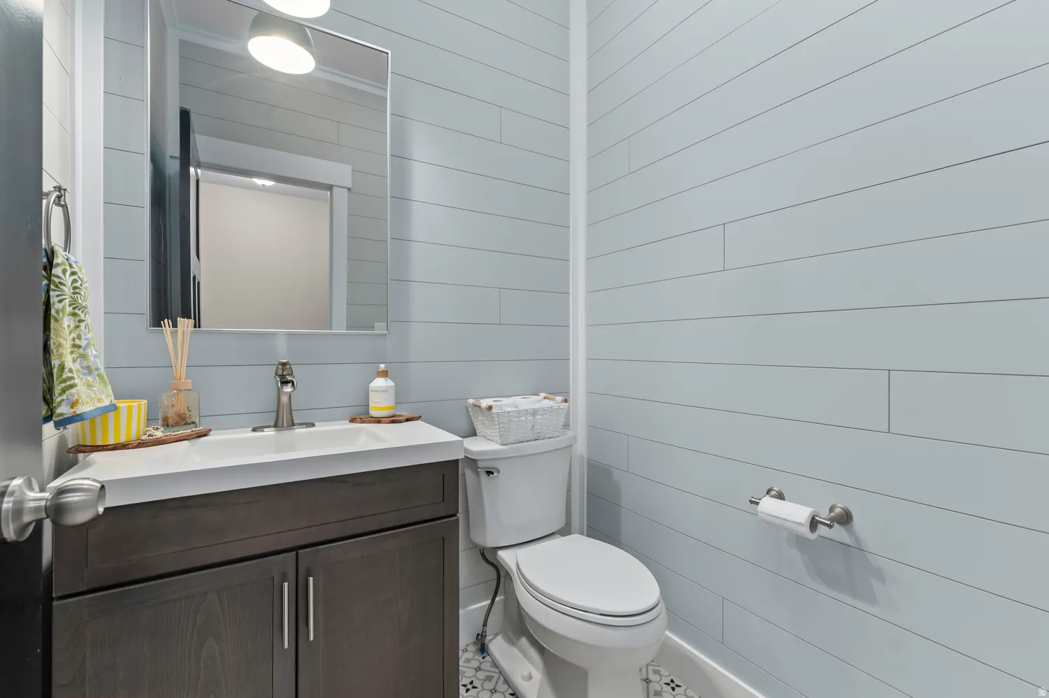Integrated vanity with a white countertop and undermount sink, brushed nickel faucet, and wood-finish cabinetry