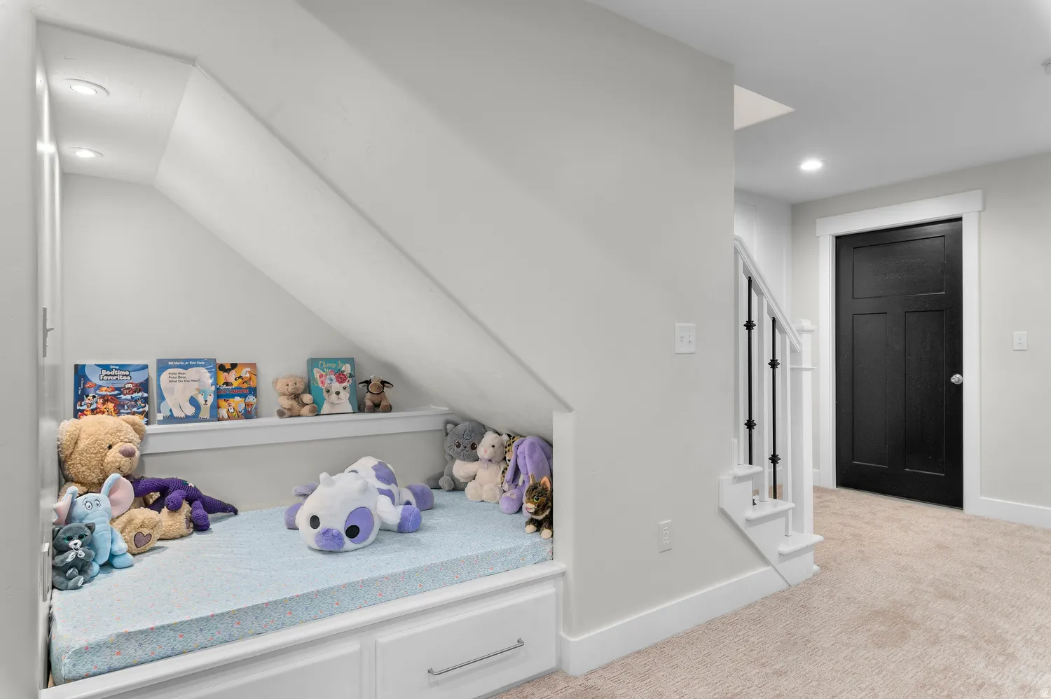 Built-in under-stair storage with recessed lighting, white trim, three-panel black interior door, and carpeted flooring