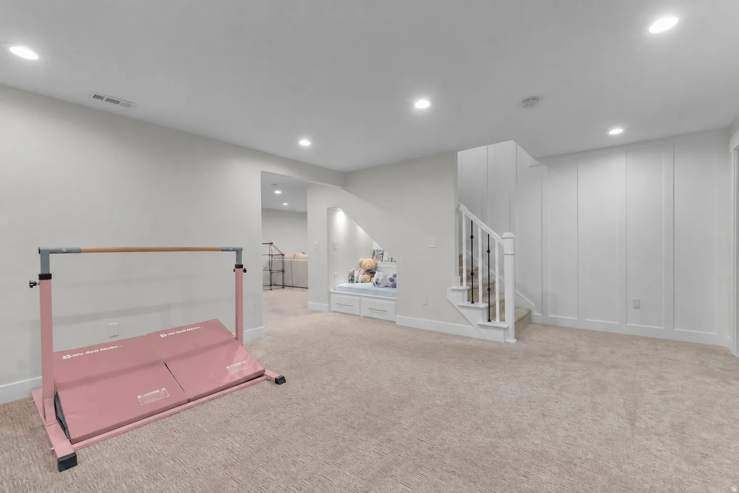 Recessed lighting illuminates a carpeted room featuring a built-in window seat with integrated storage