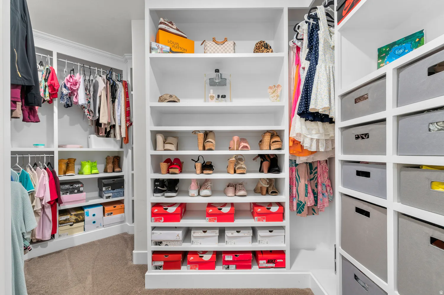 Built-in closet system featuring white shelving, multiple hanging rods, and dedicated shoe storage