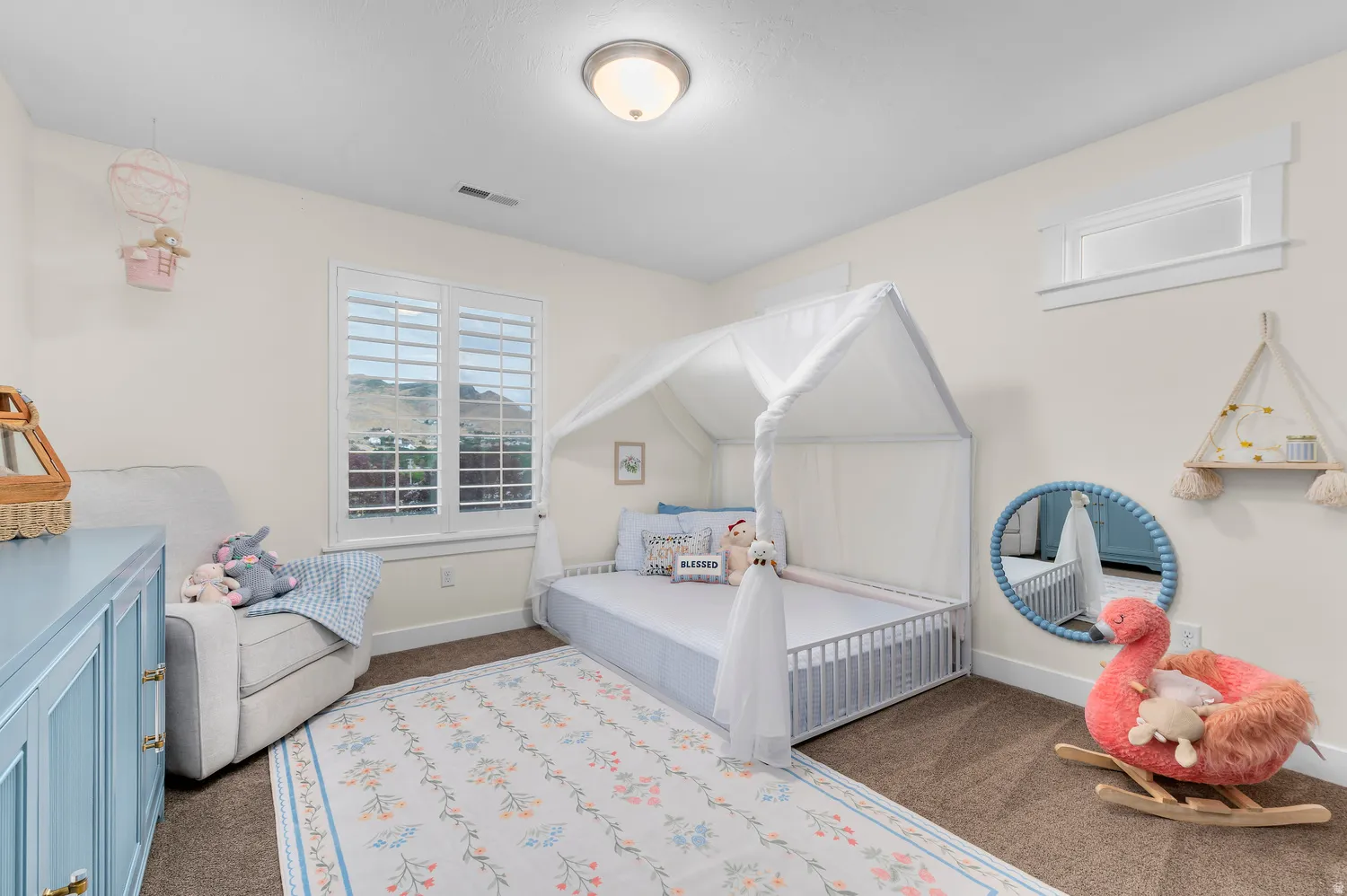 Plush carpeted flooring, window with plantation shutters, additional high window, and a flush mount ceiling light fixture