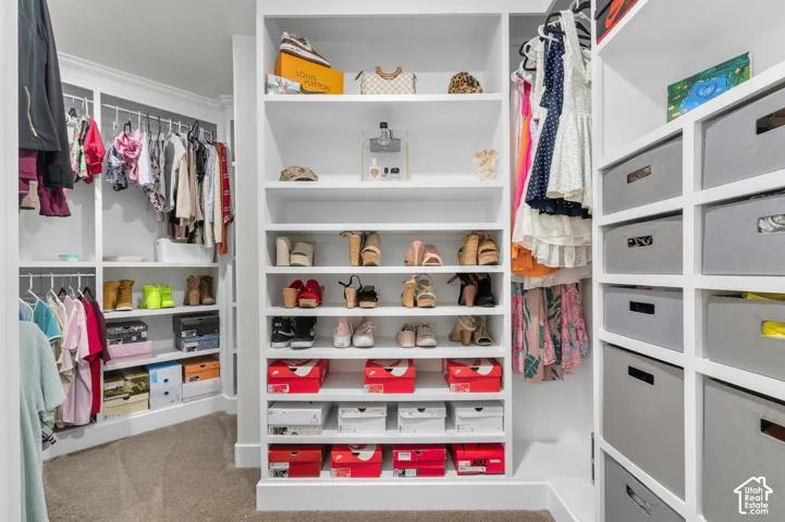 Built-in closet system featuring white shelving, multiple hanging rods, and dedicated shoe storage