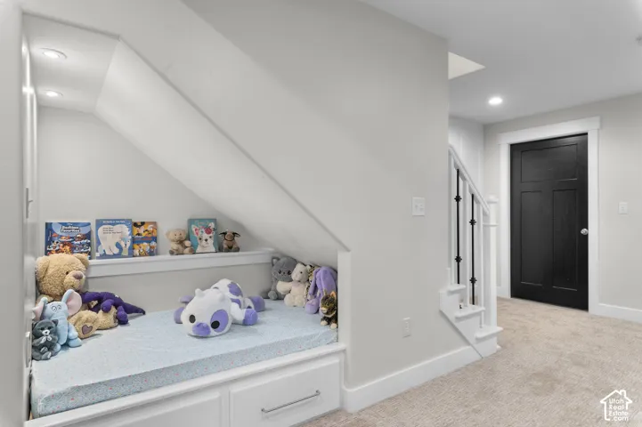 Built-in under-stair storage with recessed lighting, white trim, three-panel black interior door, and carpeted flooring