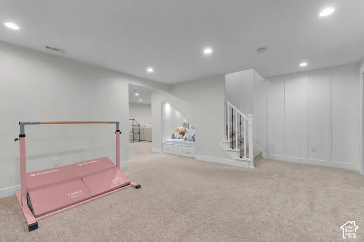 Recessed lighting illuminates a carpeted room featuring a built-in window seat with integrated storage