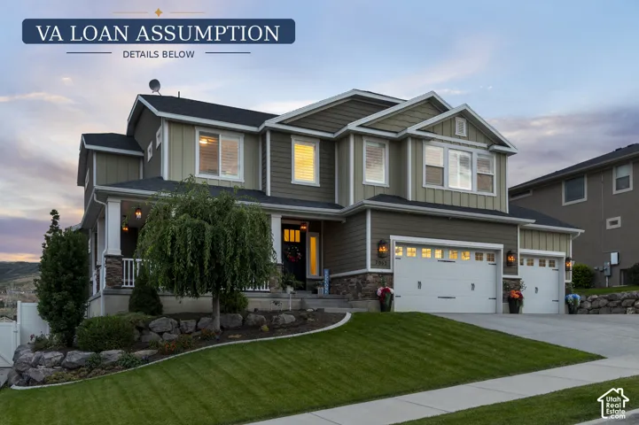 Two-story exterior with multi-toned siding, a covered front porch with white railings, and stone accents