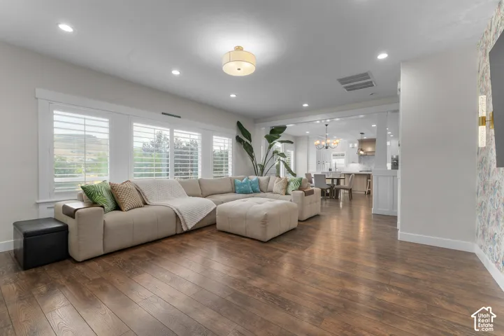 Wood-finish flooring, recessed lighting, and a drum ceiling fixture illuminate this open-concept space