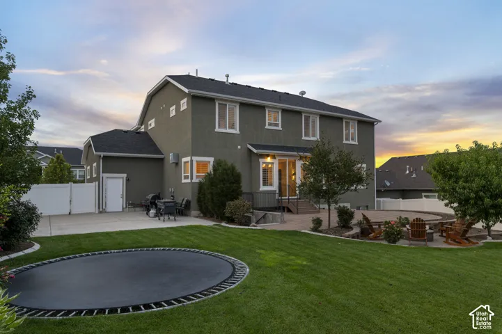 Spacious rear exterior featuring a multi-level patio, built-in fire pit, and a large lawn area
