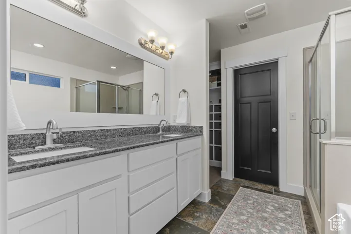 Dual vanity with undermount sinks, granite countertops, and white cabinetry