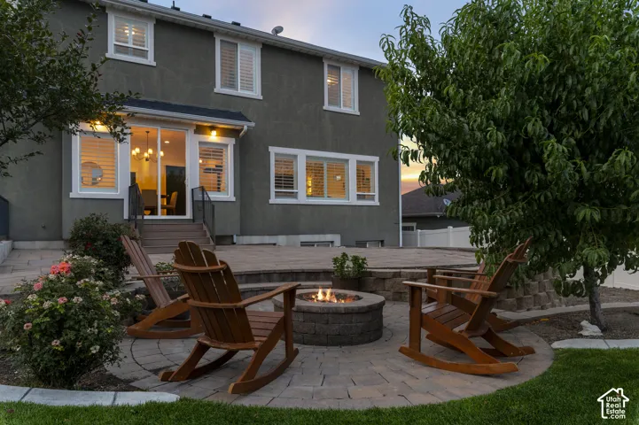 Expansive paver patio with a built-in fire pit, surrounded by mature landscaping