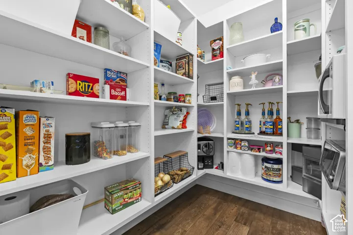 Custom built-in pantry shelving with white finishes and wood-finish flooring