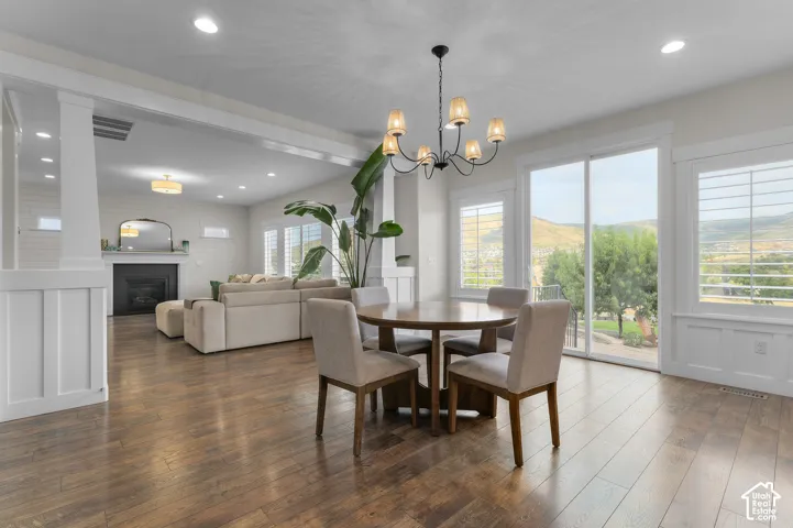 Wood-finish flooring throughout, a chandelier light fixture, sliding glass doors, built-in window shutters, and a fireplace with a mantel