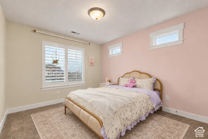 Wall-to-wall carpeting with multiple windows, including a large window with white plantation shutters and two transom windows