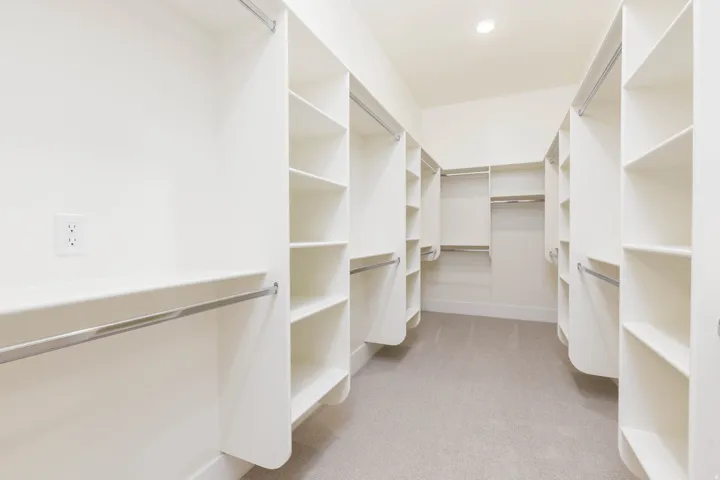 Walk-in closet featuring extensive built-in shelving, multiple hanging rods, recessed lighting, and light-toned carpet