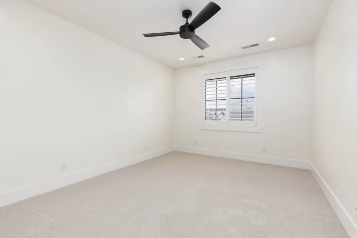 Recessed lighting, ceiling fan, window with plantation shutters, light-toned carpet, and neutral wall tones