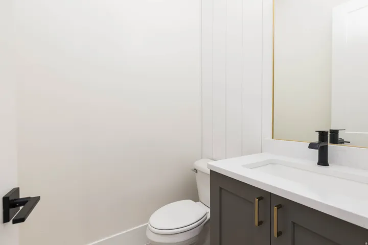 Modern vanity with white countertop, integrated sink, matte black faucet, and gold-finish hardware