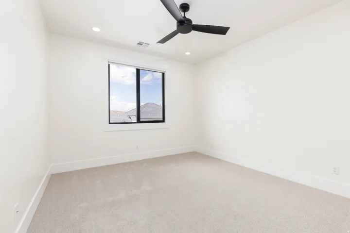 Recessed lighting, ceiling fan, large window with black trim, and light-toned carpeting