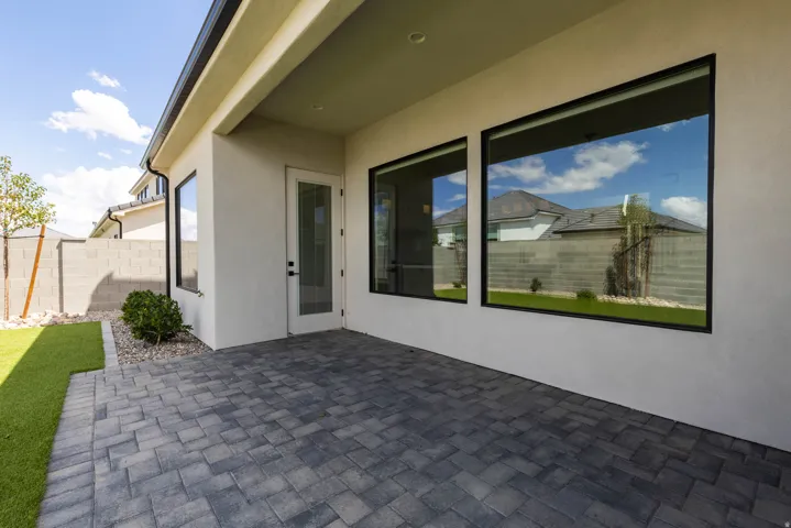 Outdoor living area featuring a covered patio, paver flooring, and artificial turf