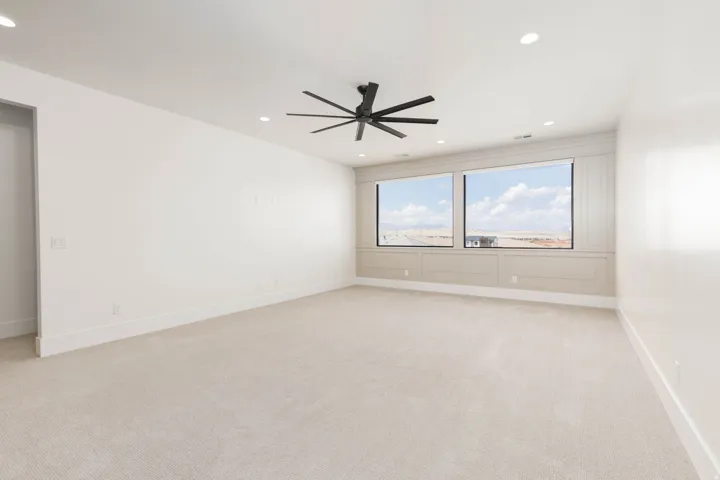 Spacious room featuring neutral carpeting, recessed lighting, and a contemporary ceiling fan