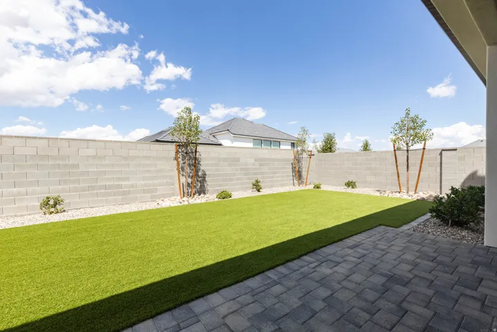 Paver patio area, artificial turf, perimeter block wall, and decorative rock landscaping