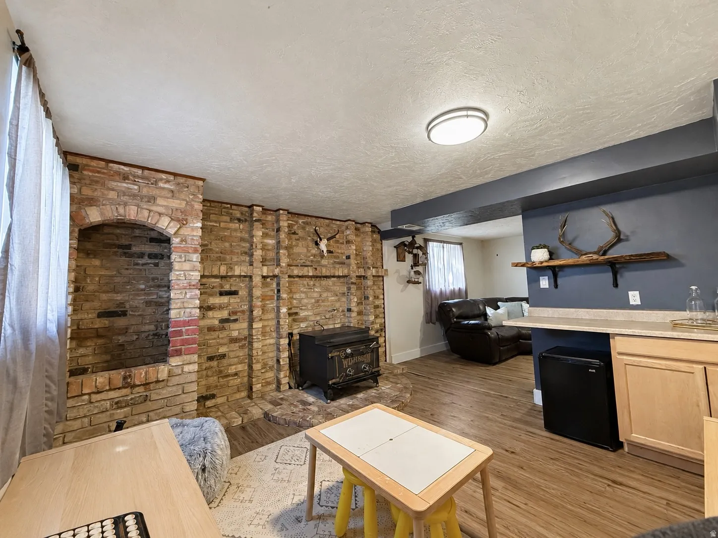 Huge basement family room with original brick, wood-burning stove, and dry bar. This area could be converted into a 4th bedroom.