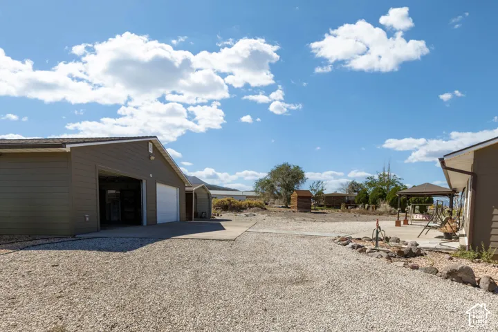 Detached garage building with multiple bays, gravel driveway, concrete pad, and a separate patio area with a gazebo