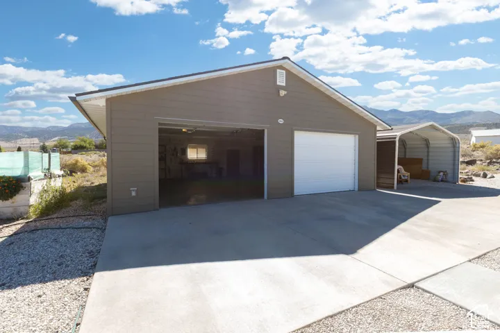 Detached garage with two bays, concrete driveway, and an additional metal carport structure