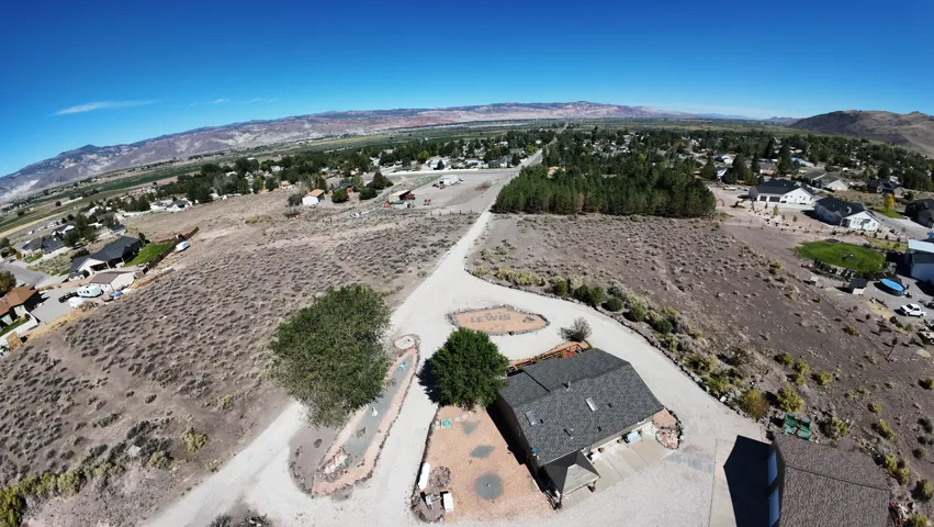 Expansive land parcel with unpaved driveway, mature trees, and distant mountain backdrop