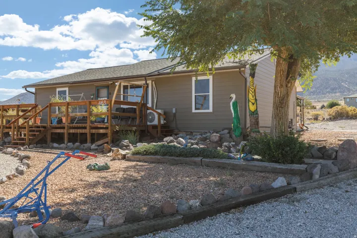 Exterior featuring a multi-level wood deck, neutral-toned siding, and a gravel landscape with rock borders