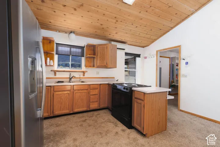 Wood-finish vaulted ceiling, stainless steel refrigerator, wood-finish cabinetry, solid surface countertops, and electric range