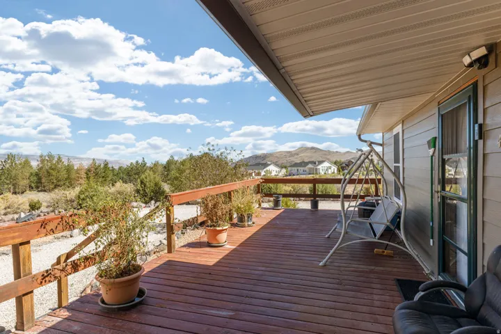 Expansive outdoor deck with wood railing, covered patio area, and exterior lighting